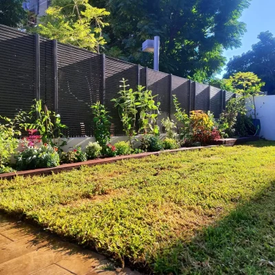 עיצוב גינה בדירת גן בתל אביב על ידי גיל בגינה, עם דשא טבעי וערוגות בסגנון ישראלי פראי הבנויות מאדני רכבת.