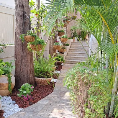 הקמת גינה בסגנון כפרי - חיפוי קרקע באמצעות טוף וחלוקי נחל, כדים עם פרחים, עציצים תלויים